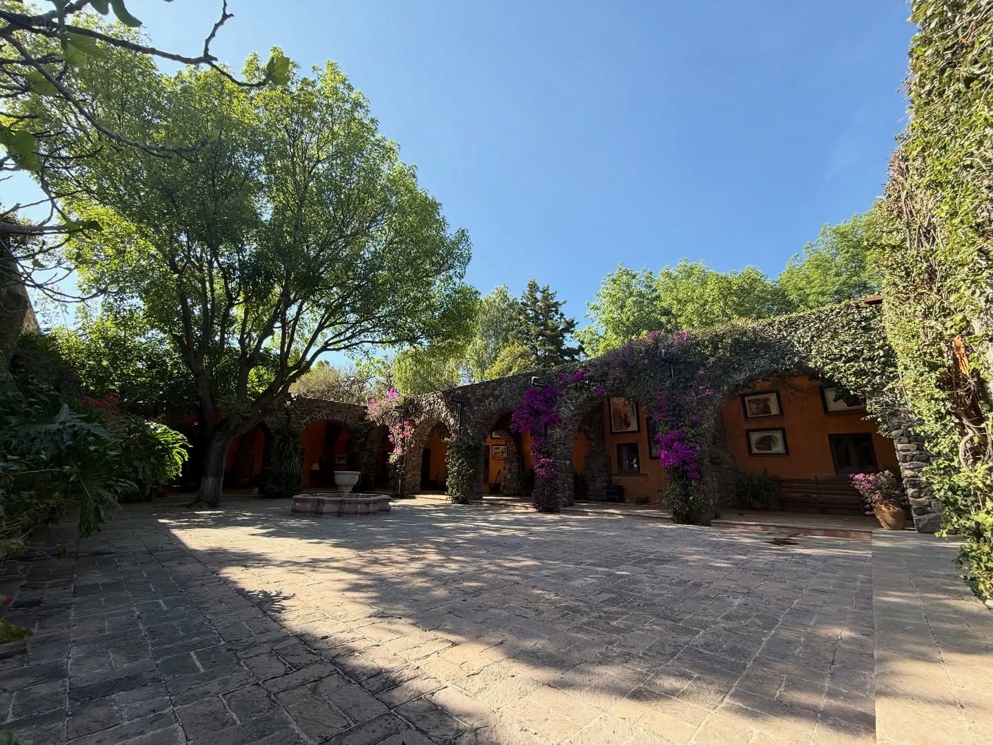 Camino empedrado entre arcos de piedra y buganvilias en Hacienda Dolores, Querétaro