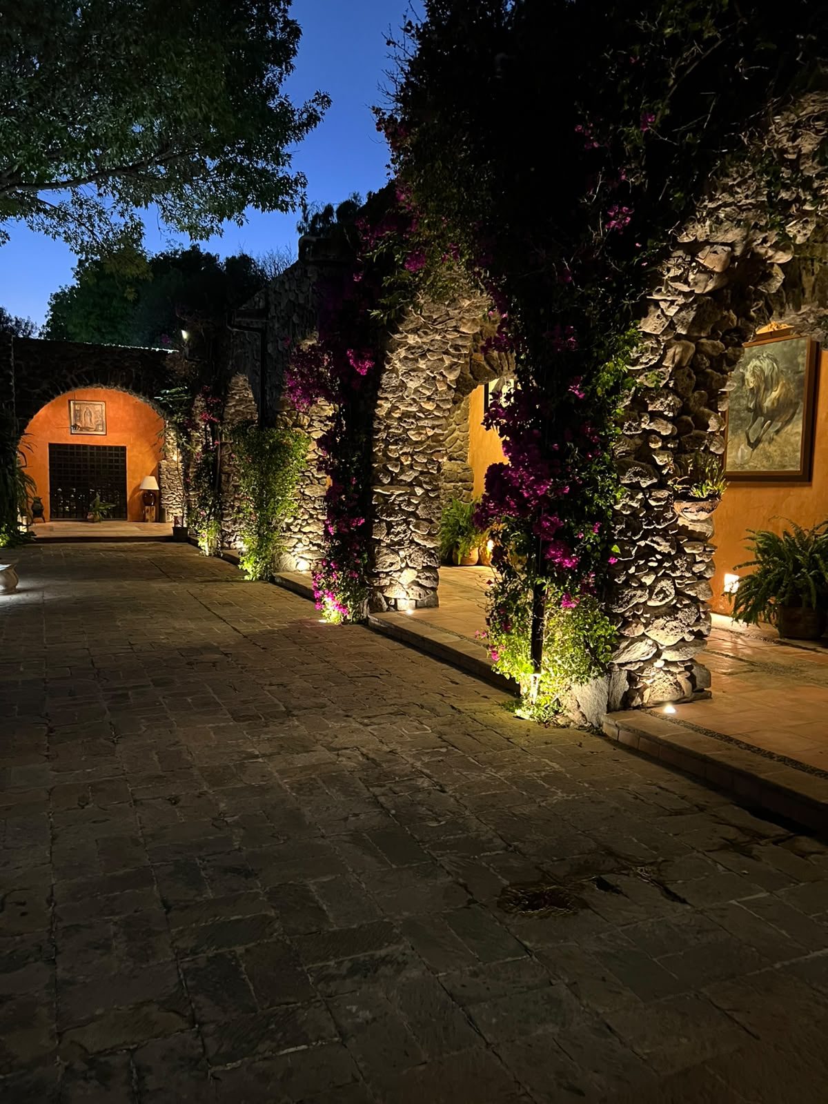 Corredor empedrado con buganvilias y arco de piedra en Hacienda Dolores, Querétaro