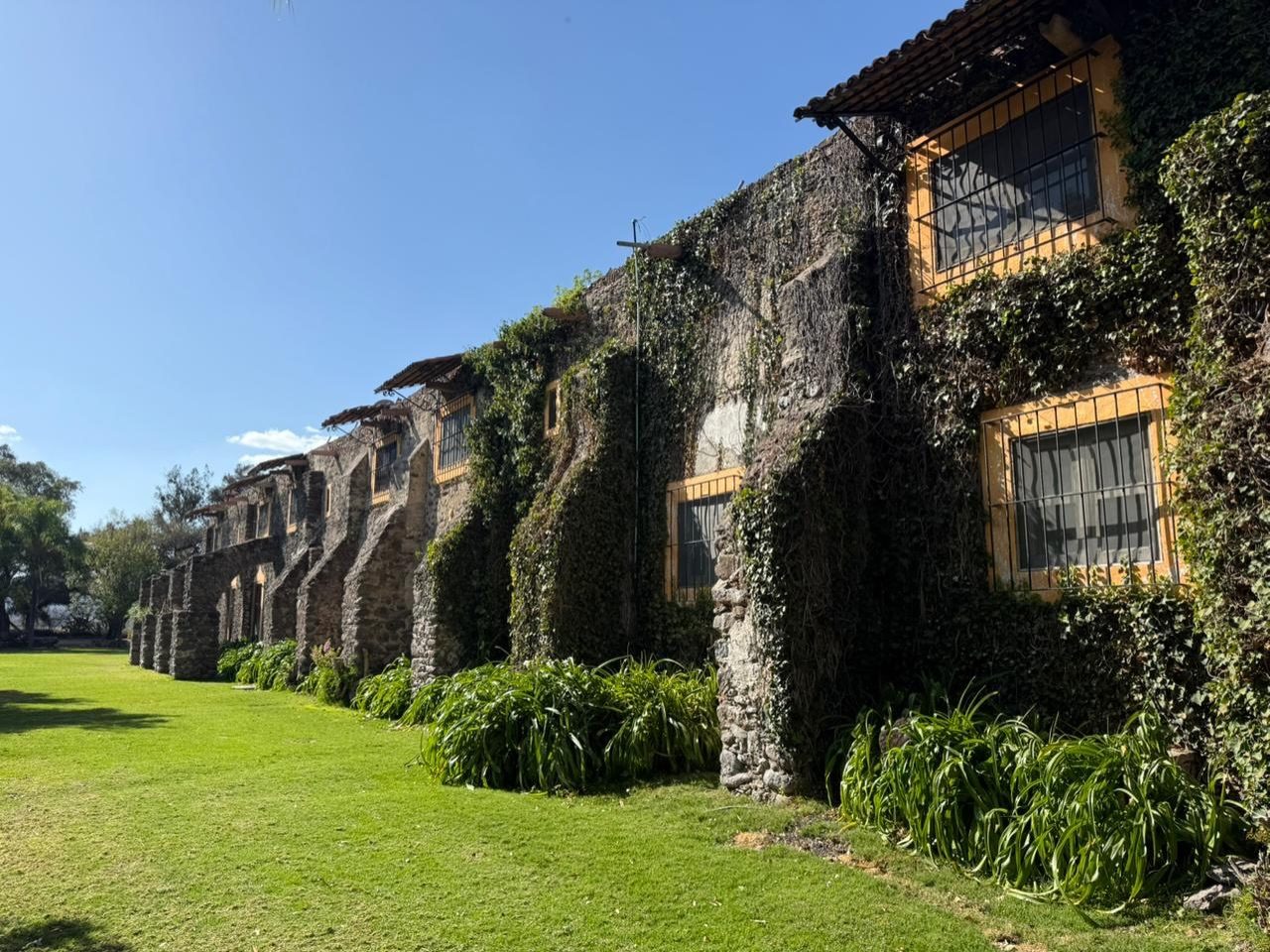 Fachada de arcos de piedra cubierta de hiedra en Hacienda Dolores, Querétaro