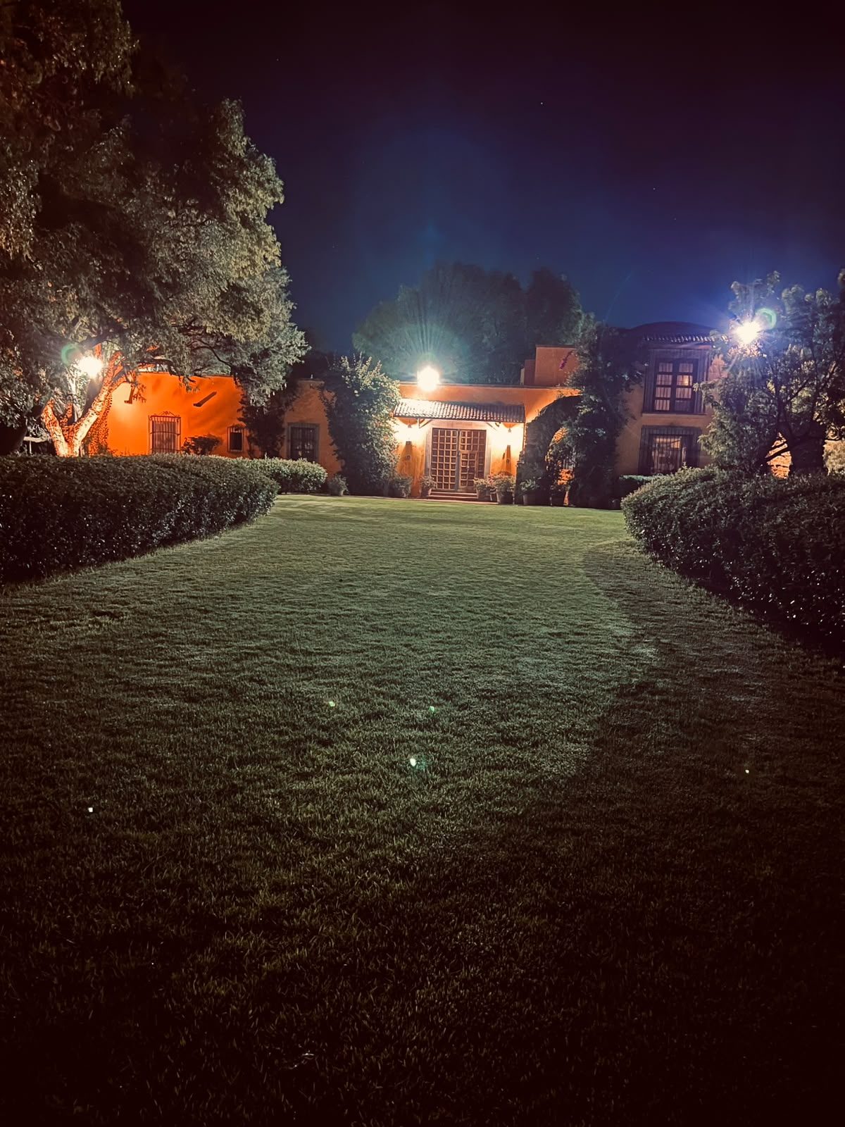 Camino empedrado iluminado hacia la casona de noche en Hacienda Dolores, Querétaro
